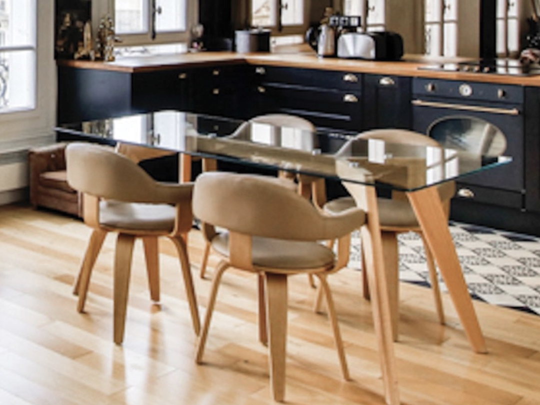 Chaise suédoise pivotante beige en bois clair autour d'une table en verre dans une cuisine parisienne